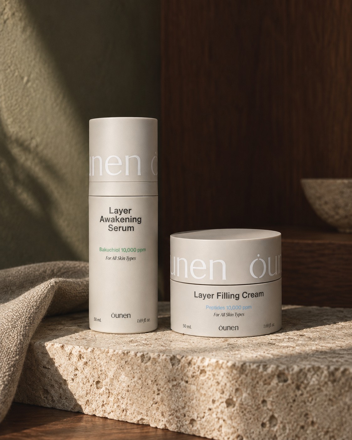 트래버틴 위에 나란히 놓인 Layer Awakening Serum과 Layer Filling Cream